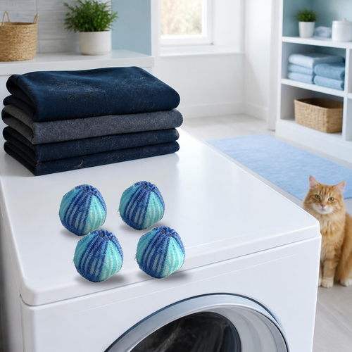 Four laundry pet hair catcher balls on a washing machine next to folded clothes and a cat